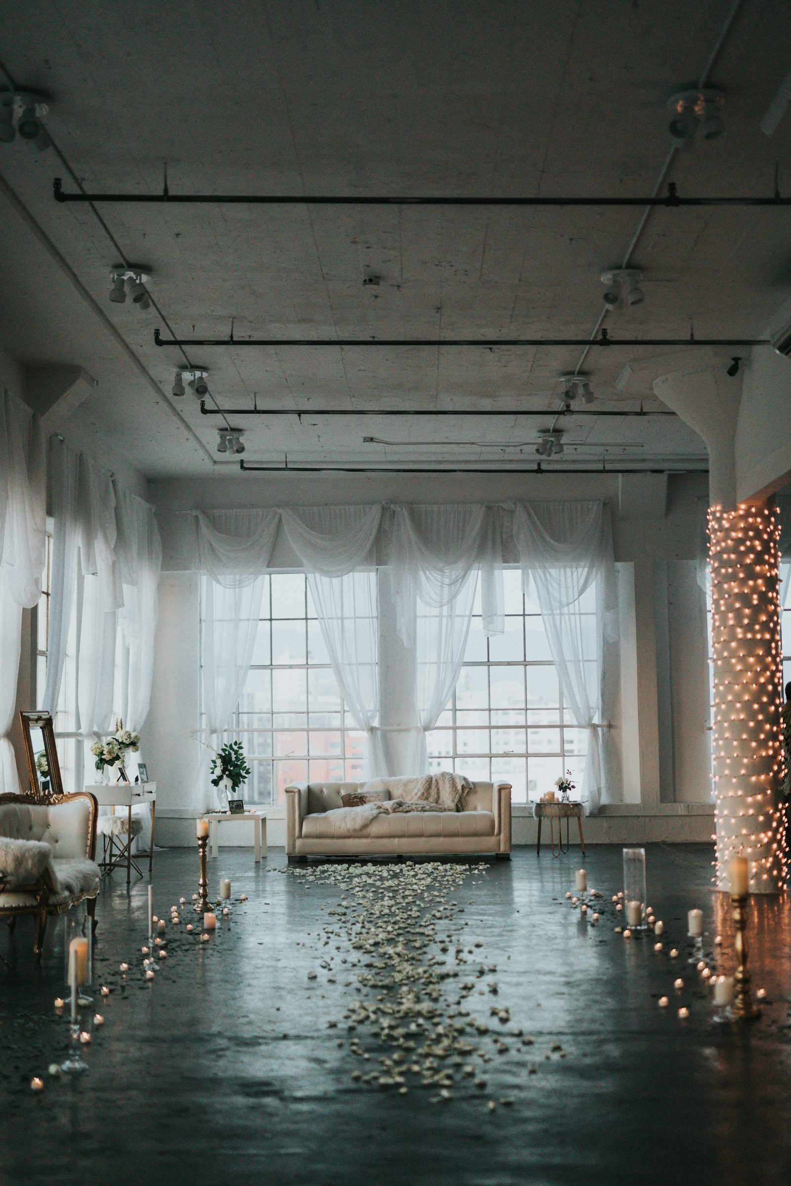 Sunlit loft with tall windows and white curtains